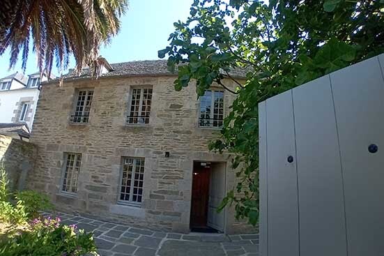 Photo d'une maison vue de face en pierre avec une toiture en ardoise
